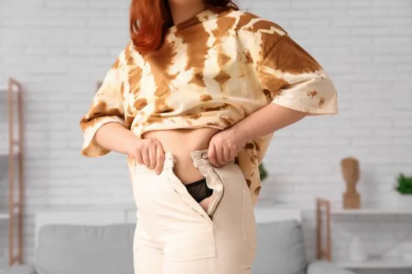 Image of woman trying to do her trousers up after pregnancy weight gain Sedgley Park