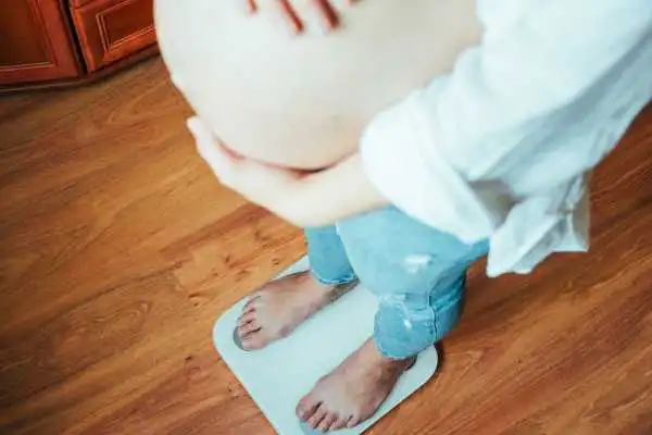 Image of woman weighing herself and experiencing weight gain through pregnancy Sedgley Park